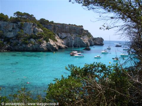 Boats anchored in turquoise cove among white cliffs and pines