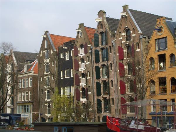 Brick gabled houses with red shutters along an Amsterdam canal