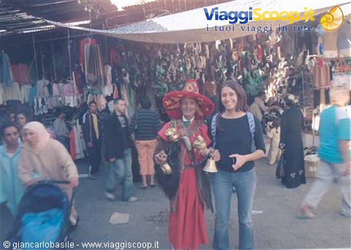 Tourist next to a red-costumed water seller in Marrakech souk