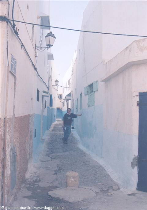 Man walks through cobblestone alley with white and blue walls in the Kasbah