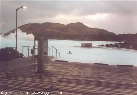 Swimmer in the milky blue waters of Blue Lagoon, wooden deck and steam