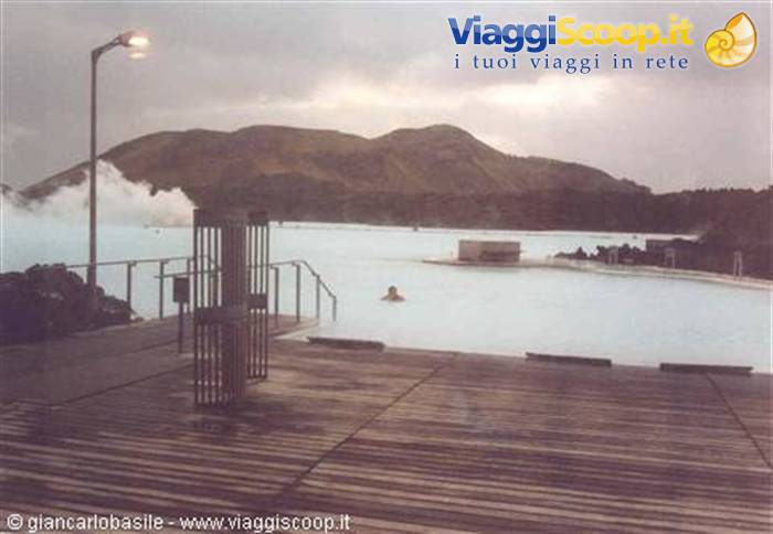 Swimmer in the milky blue waters of Blue Lagoon, wooden deck and steam