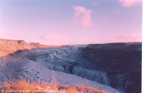 Frozen Gullfoss waterfall, mist rising between snowy rock walls
