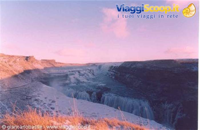 Frozen Gullfoss waterfall, mist rising between snowy rock walls