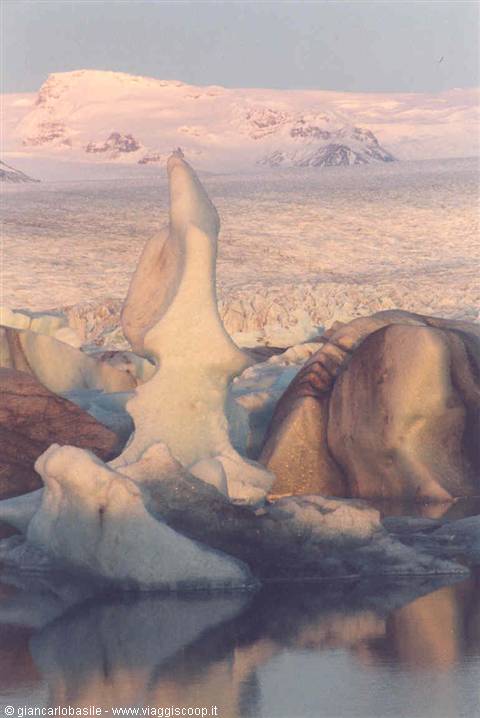 Sculpted iceberg floating in the Jökulsárlón lagoon, pink light on the glacier