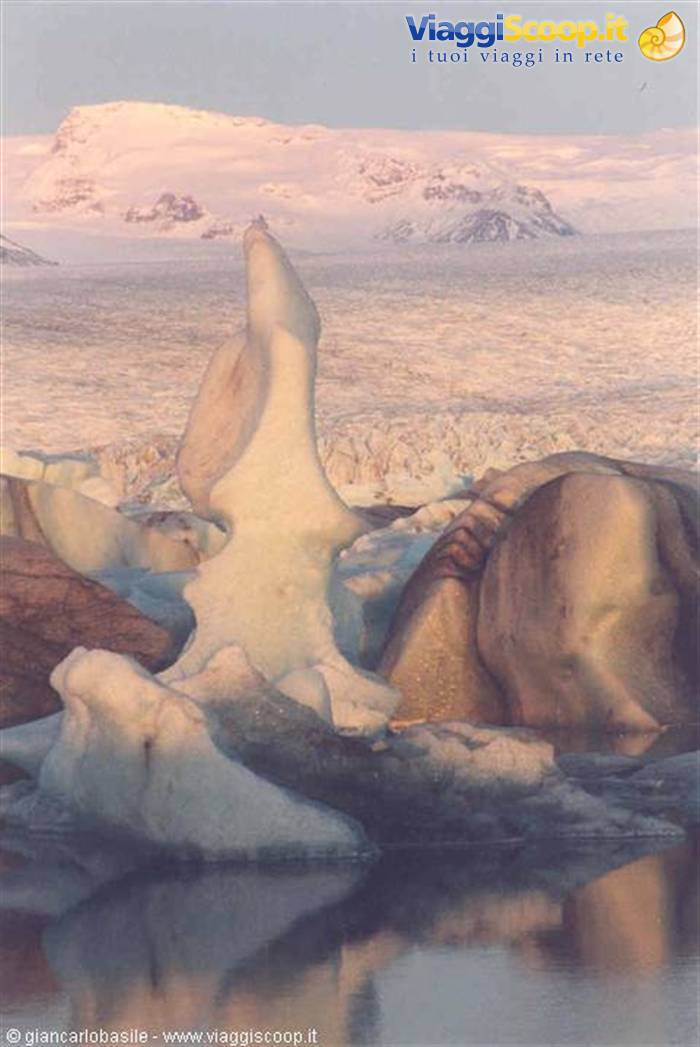 Sculpted iceberg floating in the Jökulsárlón lagoon, pink light on the glacier