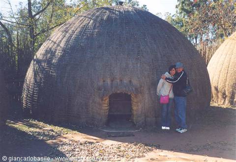 Couple in front of traditional thatched beehive hut, Lesedi Cultural Village