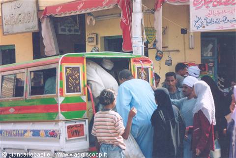 Men boarding a decorated green and red minibus, shops with Arabic signs