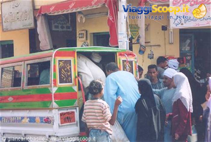 Men boarding a decorated green and red minibus, shops with Arabic signs