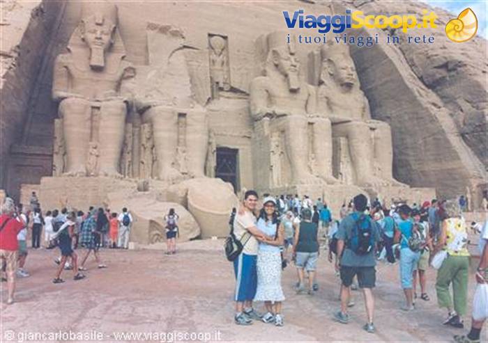 Tourists in front of the colossal statues of Abu Simbel temple, sunlit sandstone
