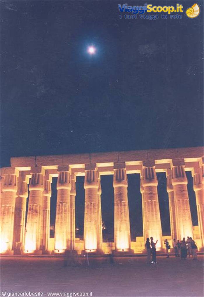 Floodlit colonnade at Luxor Temple by night, tourists under the moon