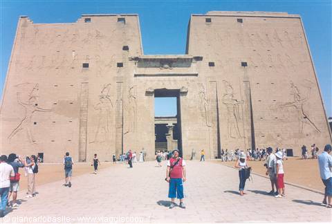 Tourists before the massive pylon of Edfu Temple, carved hieroglyphs, blue sky