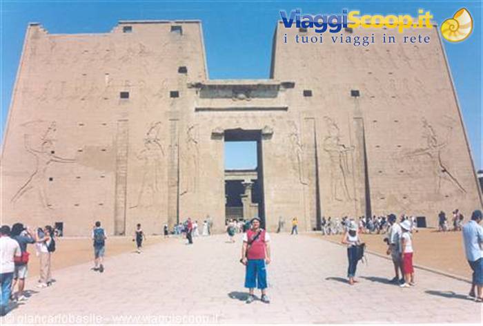 Tourists before the massive pylon of Edfu Temple, carved hieroglyphs, blue sky