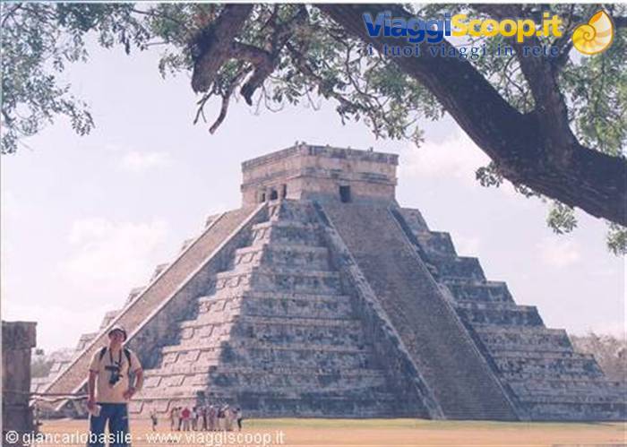 Tourist in front of El Castillo pyramid at Chichén Itzá, stone and trees