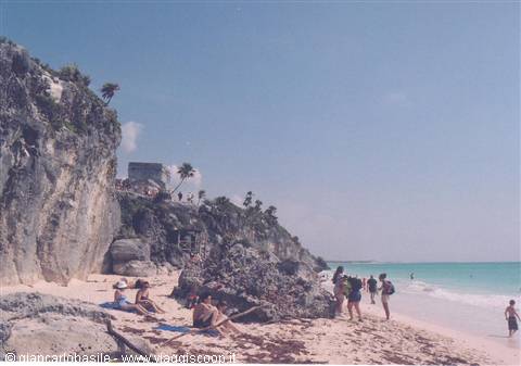 Tourists on the beach below the Mayan ruins of Tulum on the cliff