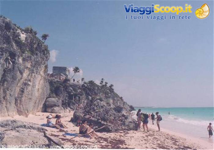 Tourists on the beach below the Mayan ruins of Tulum on the cliff
