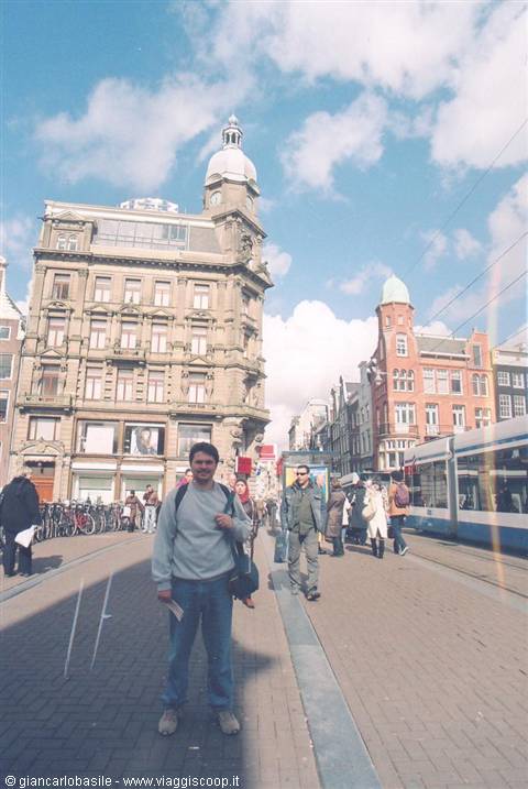 Smiling man standing beneath the historic buildings of Dam, Amsterdam