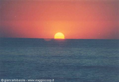 Low sun touching the sea horizon, deep red and orange sky