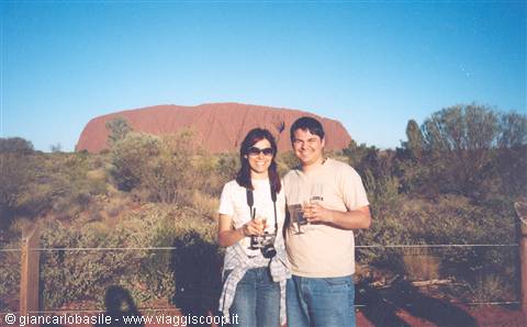 Couple with camera and drinks in front of Uluru