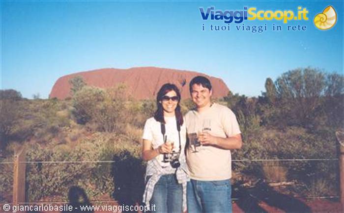 Couple with camera and drinks in front of Uluru