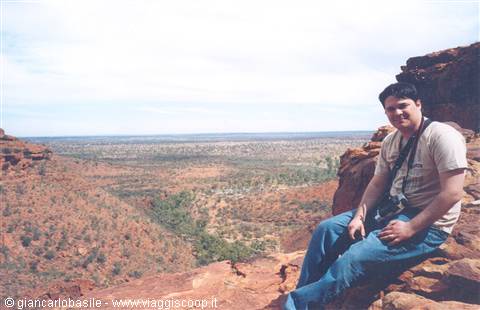Tourist sitting on the red rock of Kings Canyon, Australia