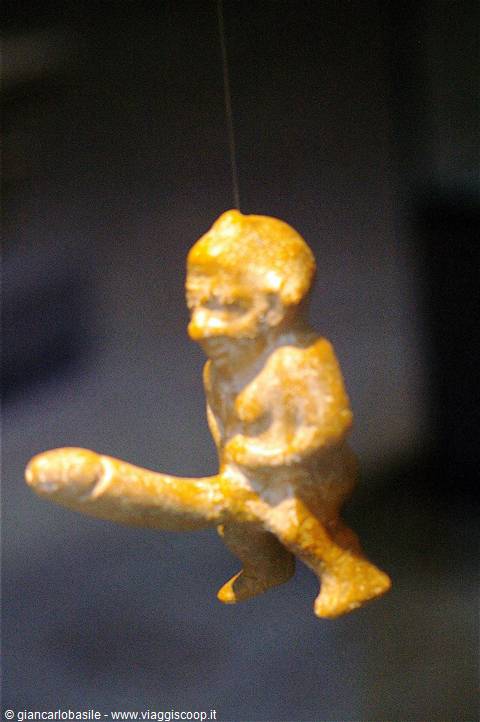 Amber amulet of a male figure, suspended, lit by warm light