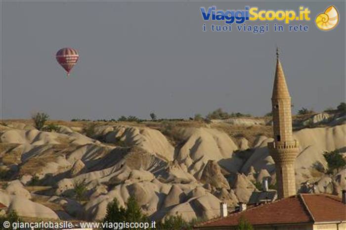 Hot air balloon over volcanic rock formations and a stone minaret, Cappadocia