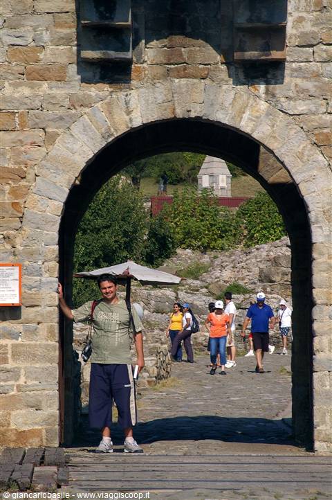 Smiling tourist under the stone fortress arch, visitors walking in the courtyard