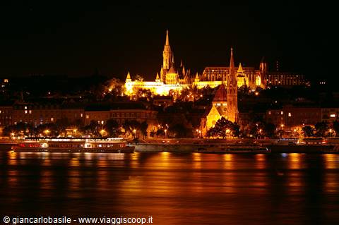 Illuminated Matthias Church at night reflects on the Danube, Budapest