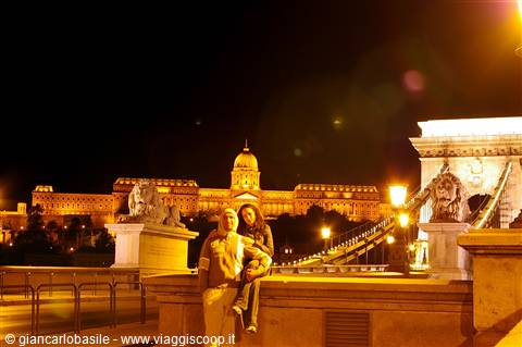 Couple on the Chain Bridge at night, Buda Castle lit up behind