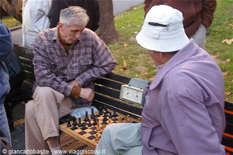 Two elderly men playing chess on a park bench
