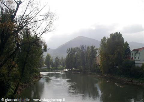 River between autumn trees and houses, misty mountain in the background