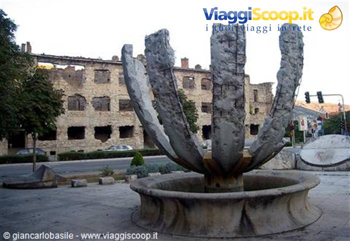 Stone petal fountain in front of Mostar's bombed building