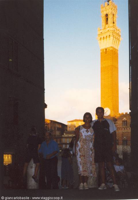 Couple posing beneath the Torre del Mangia in Siena