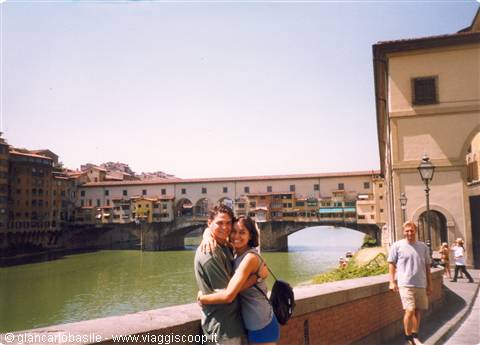 Couple hugging by the Arno river with Ponte Vecchio in Florence