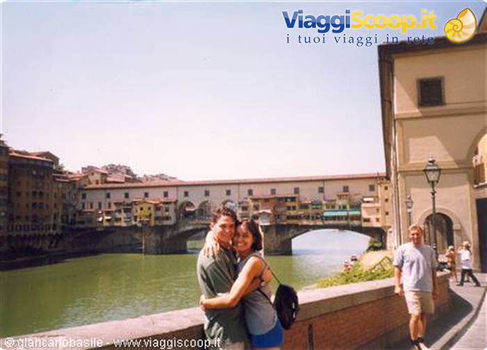 Couple hugging by the Arno river with Ponte Vecchio in Florence