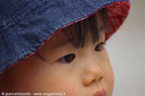 Close-up portrait of a little girl wearing a denim hat, thoughtful gaze