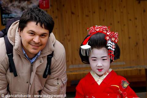 Smiling tourist next to a maiko in red kimono with kanzashi