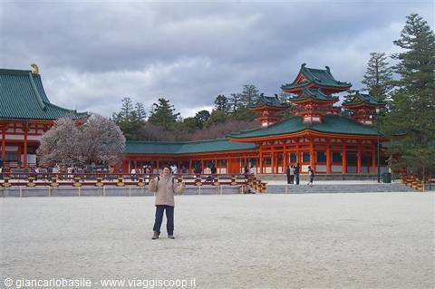 Tourist on the sandy courtyard of Heian Shrine in Kyoto, red pavilions and green roofs