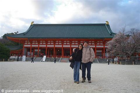 Couple posing in front of Heian Shrine's red temple with green tiled roof, Kyoto
