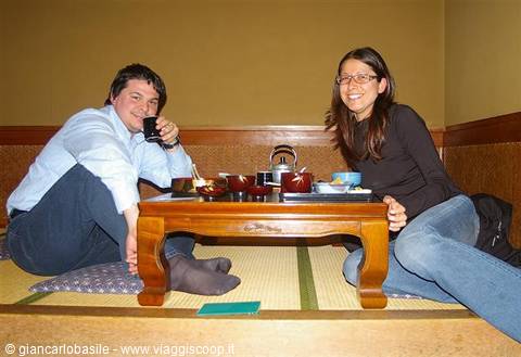 Smiling couple sitting on tatami beside a low wooden table with tea