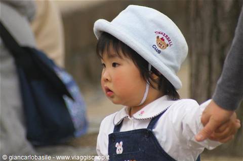 Little girl in white Tinkerbell hat holding an adult's hand