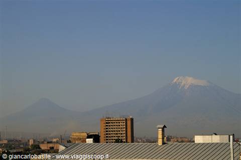 Snow-capped Mount Ararat rises above the hazy city rooftops