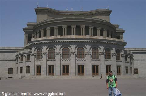 Tourist in front of Yerevan Opera Theatre, curved grey stone facade