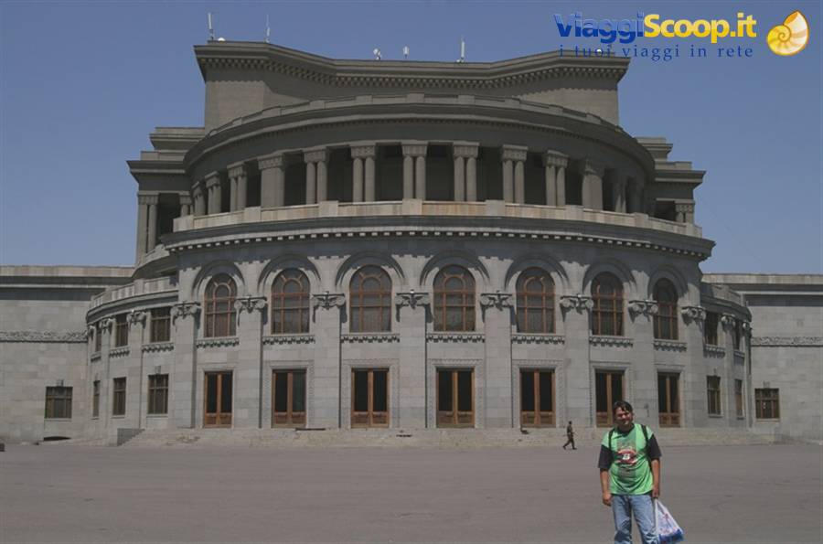 Tourist in front of Yerevan Opera Theatre, curved grey stone facade