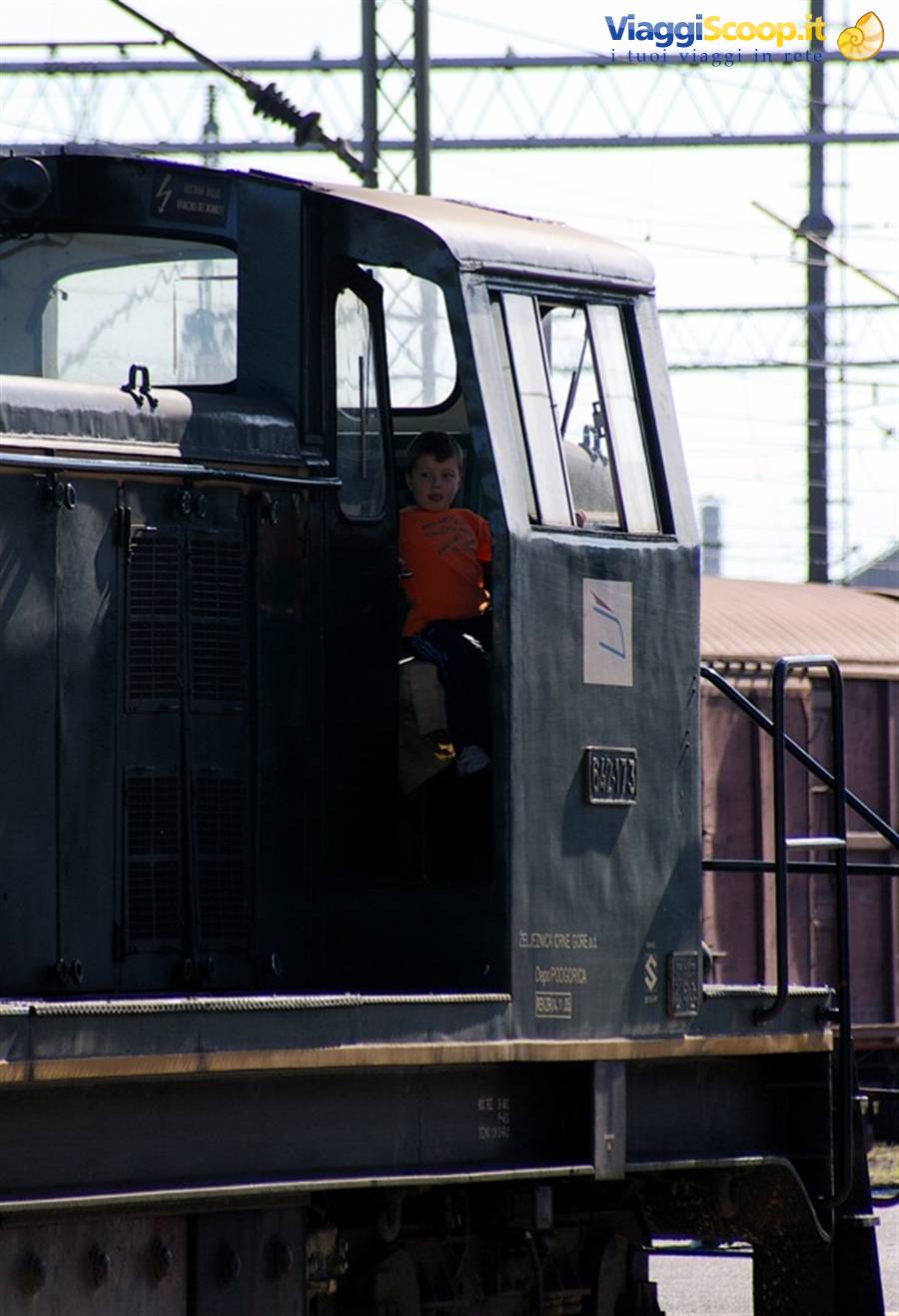 Child in orange shirt looking out from the cab of an old green locomotive