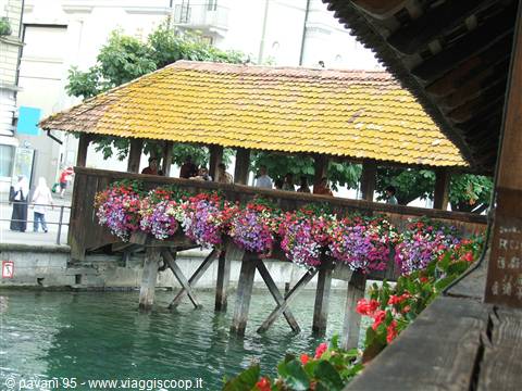 Covered wooden bridge with colorful flowers over the river, Lucerne