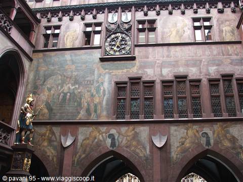 The courtyard of Basel's Rathaus with red murals, clock and statue