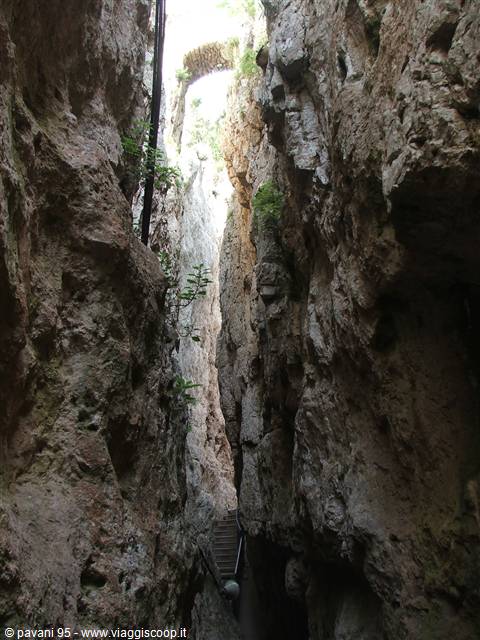 Stairs between narrow rock walls, a stone bridge above