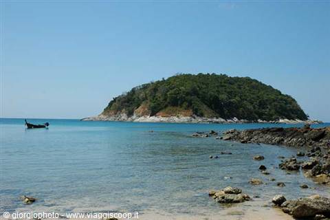 Longtail boat anchored in front of lush green tropical island